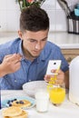 Boy with phone having breakfast in kitchen