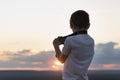 Boy photographs the sunset. Child with camera on setting sun background