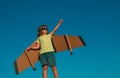 Boy pilot against a blue sky. Cute dreamer boy playing with a cardboard airplane. Childhood. Fantasy, imagination. Royalty Free Stock Photo