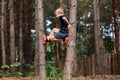 Boy in a pine forest climbed a tree and looks at the camera