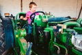 Boy with pink shirt on a farm tractor playing to be a farmer, gender roles concept