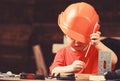 Boy play as builder or repairer, work with tools. Childhood concept. Kid boy in orange hard hat or helmet, study room Royalty Free Stock Photo