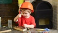 Boy play as builder or repairer, work with tools. Kid boy in orange hard hat or helmet, study room background. Child Royalty Free Stock Photo