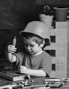 Boy play as builder or repairer, work with tools. Kid boy in orange hard hat or helmet, study room background. Childhood Royalty Free Stock Photo