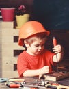 Boy play as builder or repairer, work with tools. Kid boy in orange hard hat or helmet, study room background. Childhood Royalty Free Stock Photo