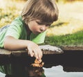 Boy play with autumn leaf ship in water, chidren in park play with leaf in river Royalty Free Stock Photo