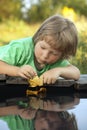 Boy play with autumn leaf ship in water, chidren in park play wi Royalty Free Stock Photo