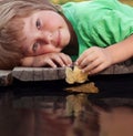 boy play with autumn leaf ship in water, chidren in park play with leaf in river