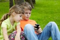 Boy play electronic game, sister sits next to him