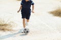 Boy play football on the dry soil ground Royalty Free Stock Photo