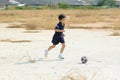 Boy play football on the dry soil ground Royalty Free Stock Photo