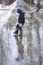 Boy play in ice puddle during winter. Royalty Free Stock Photo