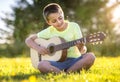 Boy playing acoustic guitar in a field at sunset Royalty Free Stock Photo