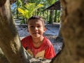 A boy is playing alone around a tree at his home.