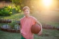 Boy playing basketball. Child holding a tball in his hands on a sunset summer day Royalty Free Stock Photo