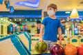 Boy playing bowling with medical masks during COVID-19 coronavirus in bowling club Royalty Free Stock Photo