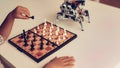 Boy Playing Chess with a Small Robot at Table