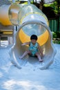 Boy playing on children`s slides. Child Playing slider at outdoor summer playground. Child playing slider on sand ground. Kid sitt Royalty Free Stock Photo