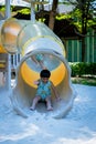 Boy playing on children`s slides. Child Playing slider at outdoor summer playground. Child playing slider on sand ground. Kid sitt Royalty Free Stock Photo