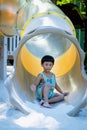 Boy playing on children`s slides. Child Playing slider at outdoor summer playground. Child playing slider on sand ground. Kid sitt Royalty Free Stock Photo