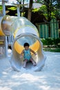 Boy playing on children`s slides. Child Playing slider at outdoor summer playground. Child playing slider on sand ground. Kid sitt Royalty Free Stock Photo