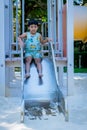 Boy playing on children`s slides. Child Playing slider at outdoor summer playground. Child playing slider on sand ground. Kid sitt Royalty Free Stock Photo