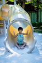 Boy playing on children`s slides. Child Playing slider at outdoor summer playground. Child playing slider on sand ground. Kid sitt Royalty Free Stock Photo