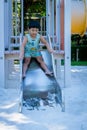 Boy playing on children`s slides. Child Playing slider at outdoor summer playground. Child playing slider on sand ground. Kid sitt Royalty Free Stock Photo