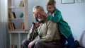 Boy playing and closing grandfather eyes, having fun together on weekends Royalty Free Stock Photo