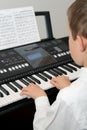 Boy playing electric piano from note sheet