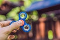 Boy playing with fidget spinner. Child spinning spinner on the playground. Blurred background