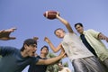 Boy (13-15) playing football with group of young men low angle view.