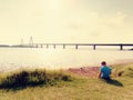 Boy is playing game on offshore, view to the big traffic bridge over bay . The two road bridge with high towers Royalty Free Stock Photo