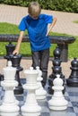 Boy playing giant chess outdoors in park. Child thinking strategically about his next move. Royalty Free Stock Photo