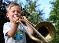 Boy playing the golden trombone outdoors Royalty Free Stock Photo