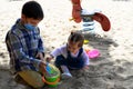 Boy playing with his little sister in a playground, they play filling a bucket of sand Royalty Free Stock Photo