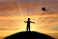 Boy playing with kite on sunset