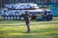 A boy is playing paintball on the field. two teams of paintball players in camouflage form with masks, helmets, guns on the field