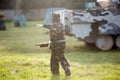 Boy is playing paintball on the field. two teams of paintball players in camouflage form with masks, helmets, guns on the field Royalty Free Stock Photo