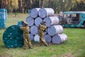 Boy is playing paintball on the field. two teams of paintball players in camouflage form with masks, helmets, guns on the field Royalty Free Stock Photo