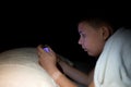 Boy playing phone at night in the dark, lying in bed Royalty Free Stock Photo