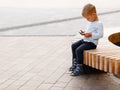 boy playing on the phone while sitting on a bench Royalty Free Stock Photo