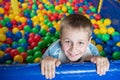 A boy in the playing room with many little colored balls