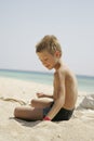 Boy playing with sand at the sea