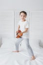 Boy playing a small guitar sitting on the bed Royalty Free Stock Photo