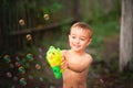 Boy playing with soap bubbles close-up and copy space. The boy in the summer shoots a water pistol. Kids games with water and bubb Royalty Free Stock Photo
