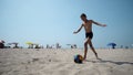 A boy playing soccer football running with a ball on sand at the beach Royalty Free Stock Photo