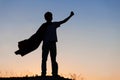 Boy playing superheroes on the sky background, teenage superhero