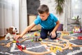 Boy playing with toy train with wooden rails while sitting on floor at home Royalty Free Stock Photo