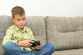 Boy playing video games with joystic sitting on sofa Royalty Free Stock Photo